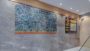 A lobby with a large wall mural of stacked books, a staircase, and a sign with event information. - Super 8 (Ningde Wanda Plaza) (Ningde)