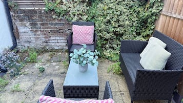 Un espace extérieur aménagé avec des meubles en osier, une table et une plante en pot.