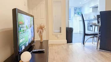 Un salon moderne avec un téléviseur à écran plat, une télécommande et un vase décoratif posé sur une table en bois.