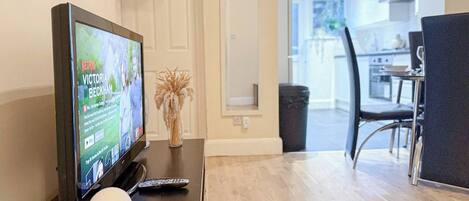 Un soggiorno moderno con una TV a schermo piatto, un telecomando e un vaso decorativo su un tavolo in legno.