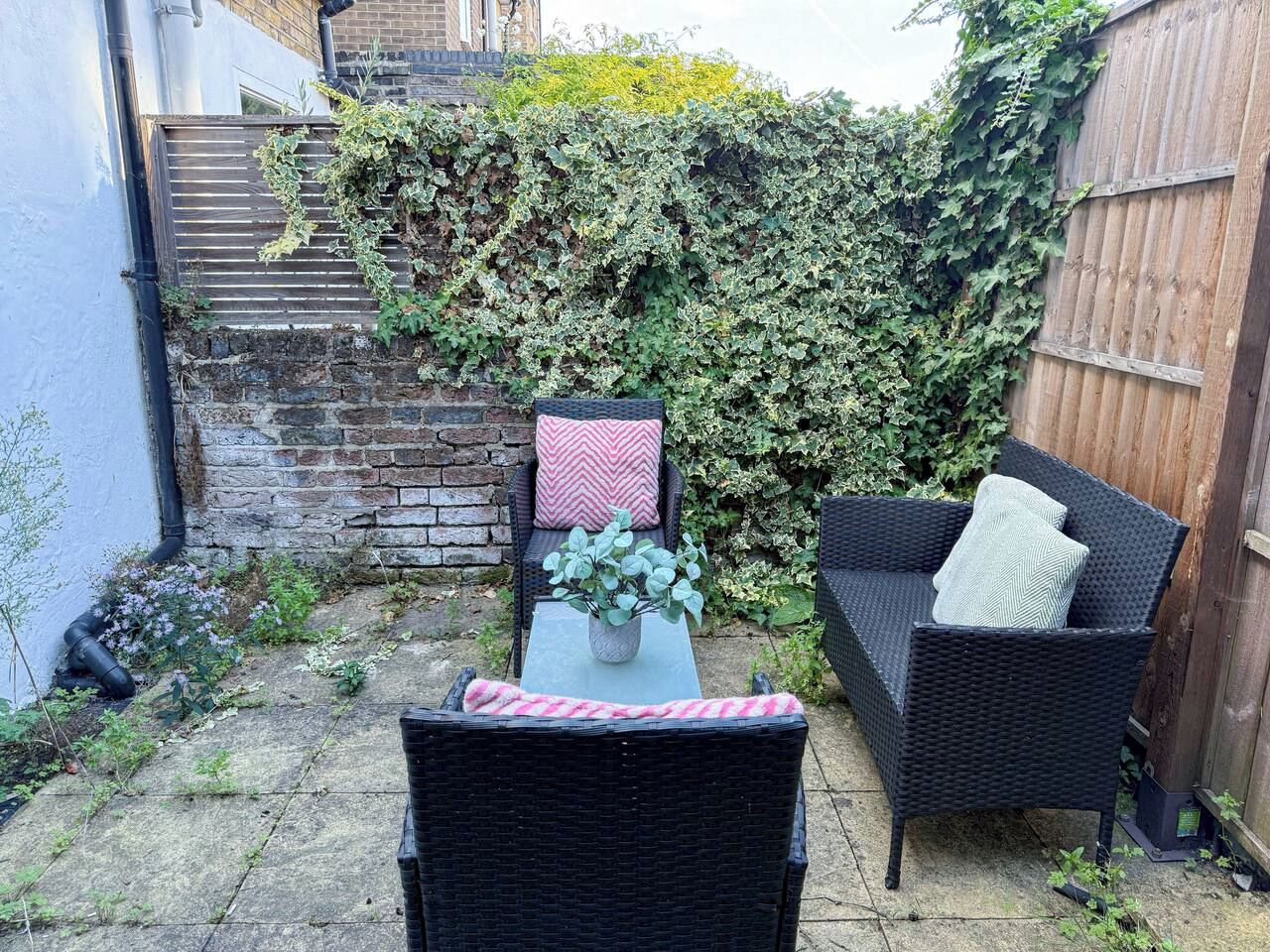 A patio with wicker furniture, a table, and a potted plant.