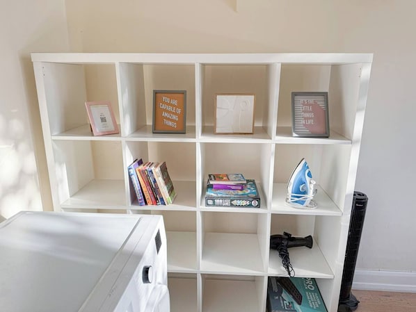 A white shelving unit with various items including books, a framed inspirational quote, and a small blue appliance.