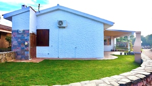 A modern house with a stone wall, a stone pathway, and a grassy lawn.