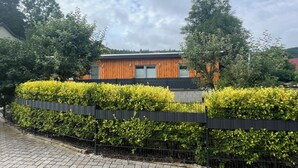 Un edifici modern amb façana de fusta, envoltat de filades i arbres ben cuidats.