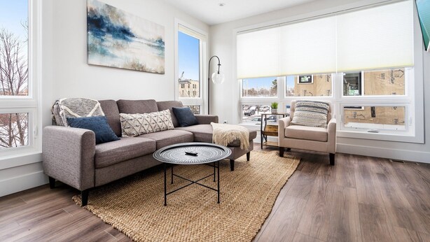 Een moderne woonkamer met een grijze bank, een ronde salontafel en een beige vloerkleed.