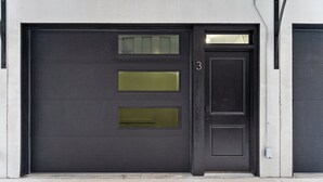 Een gesloten garagepoort met een numeriek keypad en een klein raampje.