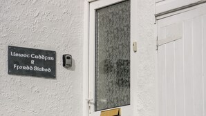 En vit dörr med nummer 8, en glasdörr med ett handtag av metall och en svart skylt med vit text ovanför dörren.