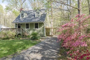 A two-story house with a front porch, a covered entryway, and a driveway leading to the house.