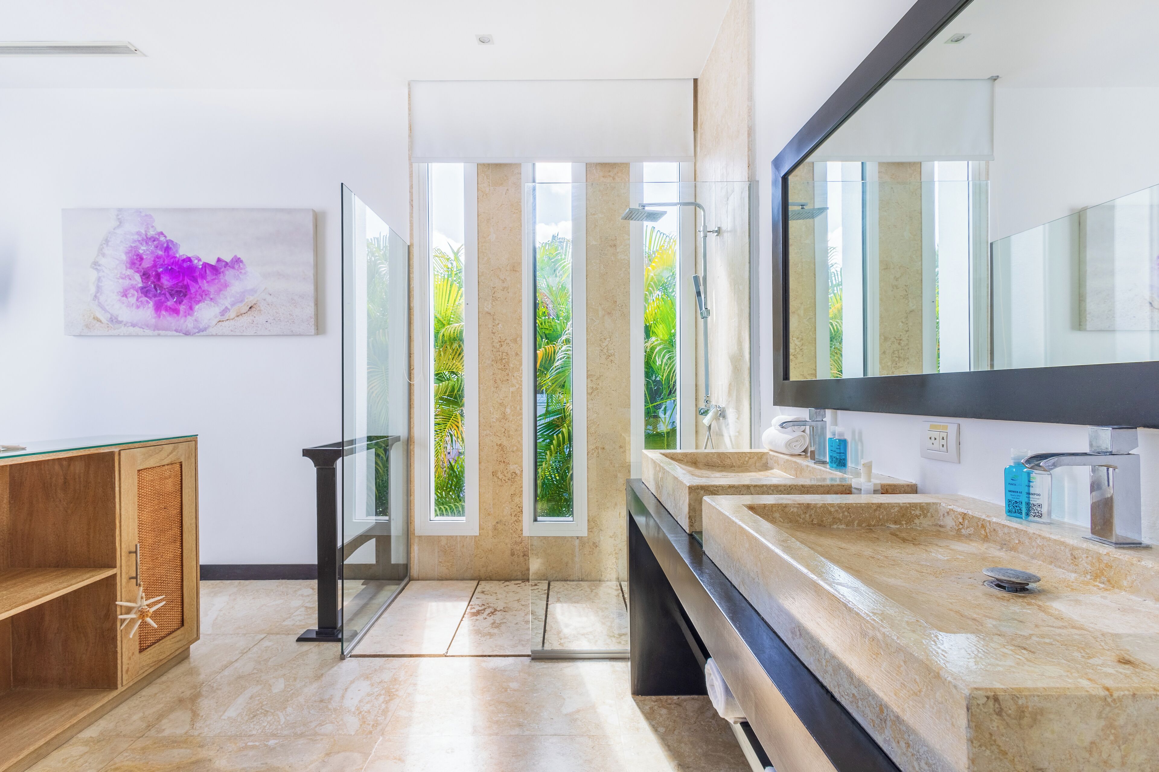 A modern bathroom with a large mirror, two sinks, and a glass shower enclosure.