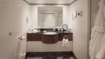 Un baño con lavamanos, espejo, toallero y zona de ducha.