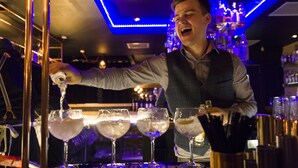 A bartender pouring a drink into a glass.
