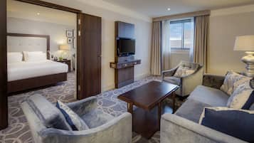 A hotel room with a bed, a TV, a sofa, a chair, and a coffee table.