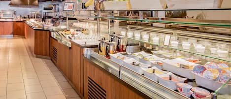 Zona de bufé con diferentes alimentos y bebidas expuestos en recipientes de vidrio.
