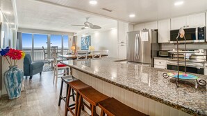 A modern kitchen with granite countertops, stainless steel appliances, and a large island with bar stools. - 1001 Waters Edge Resort 3 Bedroom Condo by RedAwning (Murrells Inlet)