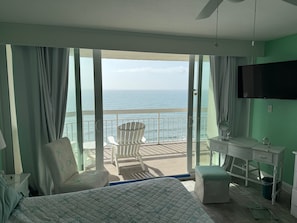 Enjoy ocean views from the balcony, featuring a large bed, desk, and chair.