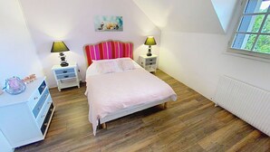 A bedroom with a bed, two bedside tables, a nightstand, a lamp, a radiator, and a window. - Gîte Lilas Sensation (Thury)