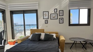 Un dormitorio con cama, una mesita y vista al mar.