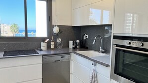 Una cocina moderna con armarios blancos, lavavajillas de acero inoxidable, un lavamanos doble y un horno empotrado.