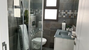 Un baño moderno con ducha envuelta en vidrio, inodoro y lavabo con espejo.