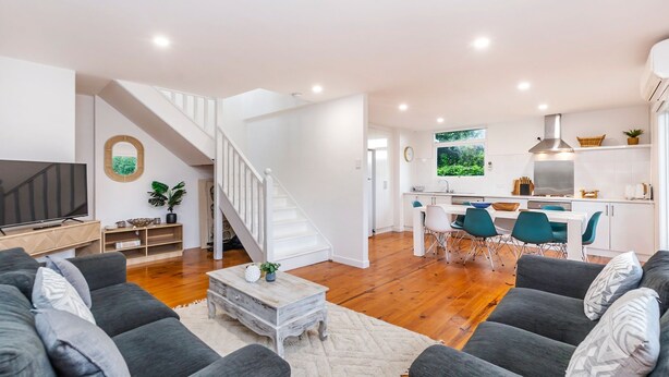 A modern living room with a staircase, a dining area, and a kitchen. - Marlin Beach House - South Beach (Port Fairy)