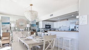 A spacious kitchen with white cabinetry, a central island, and a dining area with a bench and chairs. - Edgewater 2 Br Deluxe Gulf Front, Tower 2. Sleeps 10! (Panama City Beach)