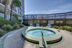A circular hot tub with a metal ladder, surrounded by a brick pathway and a wooden fence. - Edgewater 2 Br Deluxe Gulf Front, Tower 2. Sleeps 10! (Panama City Beach)
