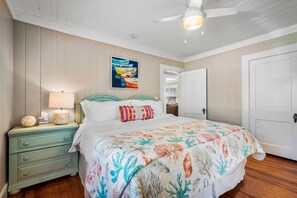 A bedroom with a bed, a nightstand, a lamp, and a painting on the wall.