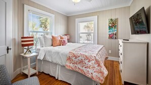 A bedroom with a bed, a nightstand, a dresser, and a ceiling fan. - Upper-Level Duplex with Partial Ocean Views 3BR/2BA (Jacksonville Beach)