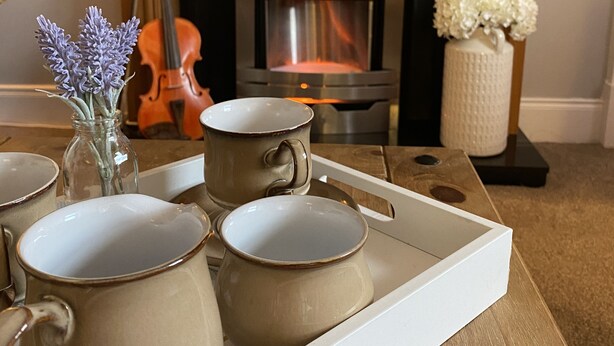 A tray with ceramic mugs and a vase with flowers on a wooden table. - The Ramblers Rest - whole apartment, pet friendly, close to amenities/walks. (Edzell)