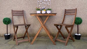 Two wooden chairs and a small table with potted plants against a textured wall. - The Ramblers Rest - whole apartment, pet friendly, close to amenities/walks. (Edzell)