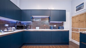 A modern kitchen with dark blue cabinets, a white countertop, and a backsplash with a textured pattern. - Old Police Office in Hawkshead by LetMeStay (Ambleside)
