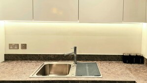A modern kitchen with a stainless steel sink, a built-in electric kettle, and a coffee maker. - 2 Bed Apartment Sleeps 4 With Free Parking (Salford)