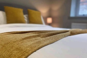 Ein Bett mit einer weißen Bettdecke und einer braunen Decke.