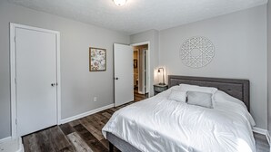 A bedroom with a bed, a nightstand, a wall decor, and a door. - Tatum's Mtn View Retreat- SAUNA-Hiking- Unit A (Madison)
