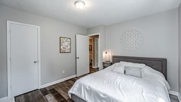 Une chambre à coucher avec un lit, une table de chevet, un élément de décoration murale et une porte.