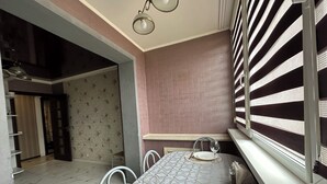 A dining area with a table set for two, a patterned tablecloth, and a window with blinds. -  PaulMarie Apartment on Podgorodskaya (Brest)