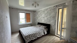 A bedroom with a bed, a window, and a door leading to a balcony. -  PaulMarie Apartment on Podgorodskaya (Brest)