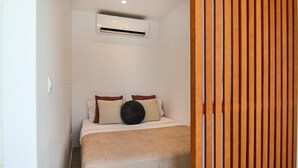 A bedroom with a bed, pillows, a blanket, and an air conditioning unit on the wall. - Phaedrus Living: Seaside Luxury Flat Harbour 102 (Paphos)
