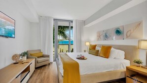 Une chambre d’hôtel équipée d’un lit, d’un bureau, d’une chaise, d’une table de chevet et offrant une vue sur l’extérieur.