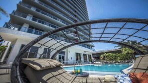 Ein modernes Hotel mit Dachpool, einer gläsernen Lounge und Blick auf die umliegenden Gebäude.