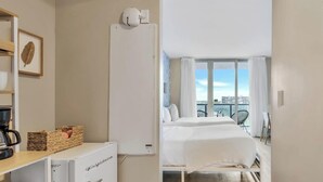 Habitación de hotel con cama, cafetera, refrigerador y vistas a la ciudad.