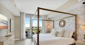 Ein Bett mit Baldachin und Blick ins Freie, ein großes Fenster mit Vorhängen und ein wandmontierter Spiegel.