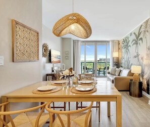 A dining area with a table set for four, a large woven pendant light, and a view of the outdoors through a sliding glass door.