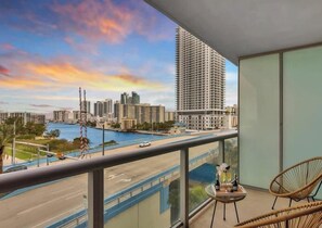 A balcony with a view of a cityscape, including high-rise buildings and a body of water. - Spectacular Apartment w/Balcony+ Pool+ Near Beach (Hallandale Beach)