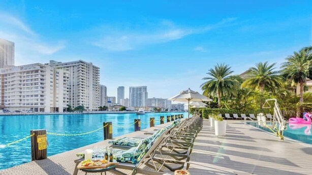 A waterfront hotel with a pool, lounge chairs, and palm trees. - Spectacular Apartment w/Balcony+ Pool+ Near Beach (Hallandale Beach)