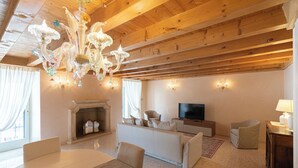 A spacious living room with a fireplace, a sofa, a TV, and a chandelier.