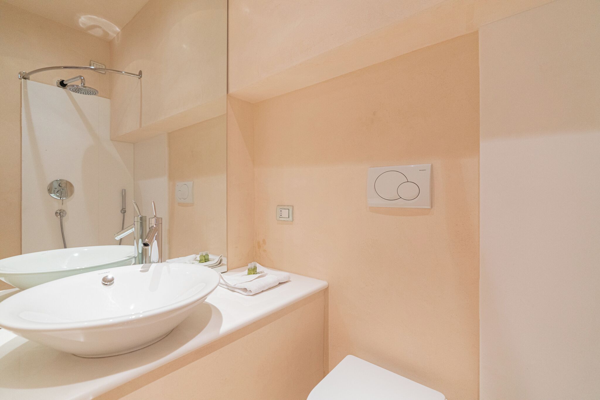 A bathroom with a double sink, a shower, and a toilet.