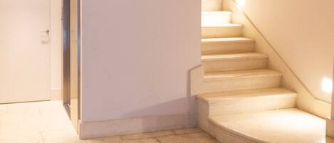A staircase with a wooden ceiling and a white wall.