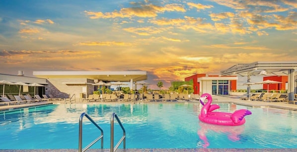 Une piscine avec des chaises longues et un flotteur en forme de flamant rose.