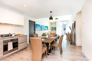 Une cuisine moderne avec un coin repas, comprenant un îlot central, un four encastré et un éclairage contemporain.